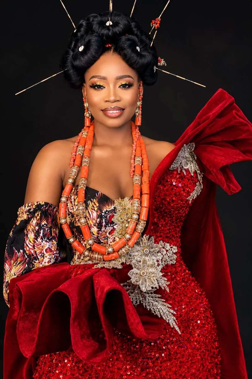 Close-up portrait of a woman wearing layered red coral beads and a red gown