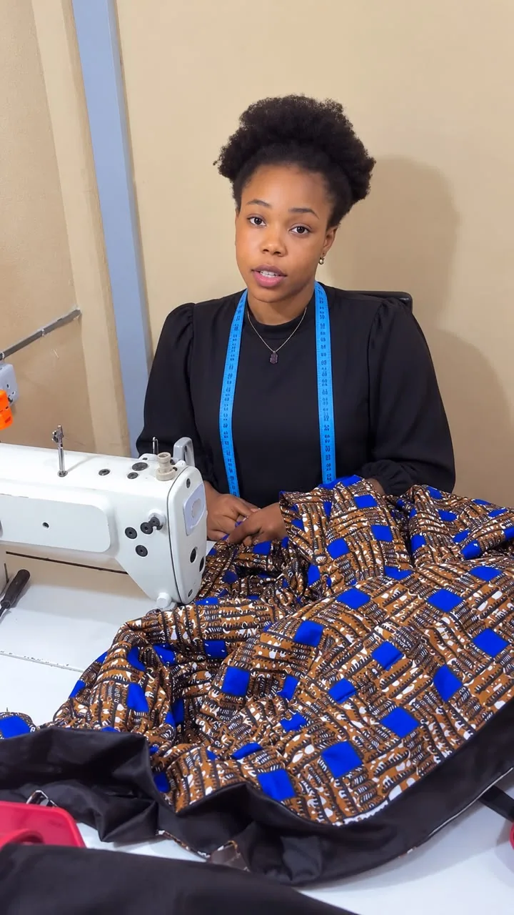 Tailor at her sewing machine with a tape measure around her neck