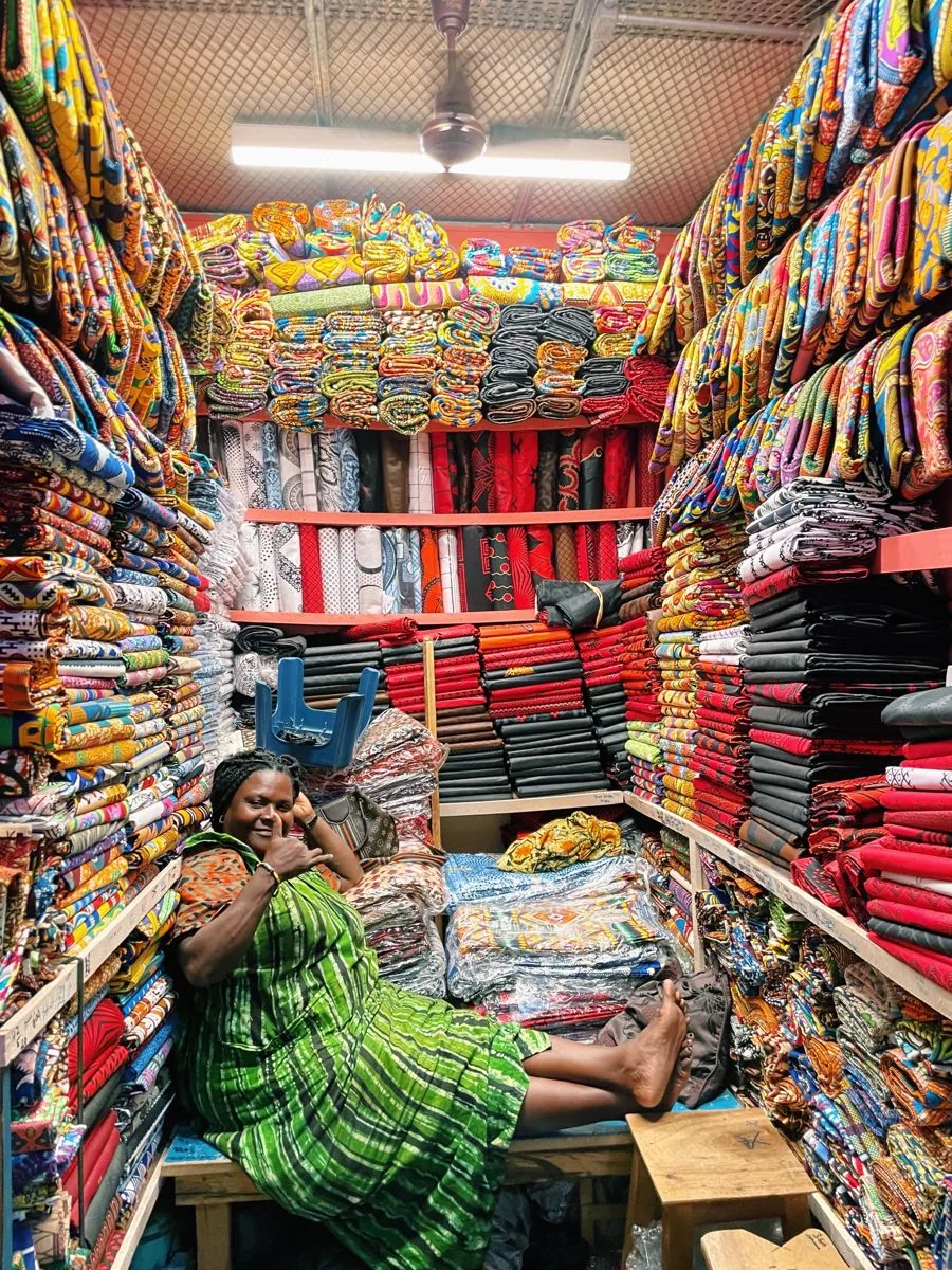 Fabric seller relaxing among rolls of cloth in her shop